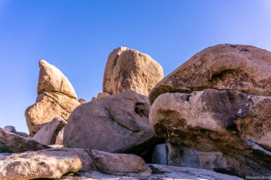 Arka planda mavi gökyüzü olan kayalık bir dağ. Kayalar büyük ve pürüzlü. Sahneye sert ve vahşi bir görünüm kazandırıyor. Gökyüzü ve kayalar arasındaki zıtlık bir huşu yaratıyor.