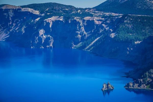 Arkasında dağlar olan güzel mavi bir göl. Göl sakin ve huzurlu. Arka plandaki dağlar sahnenin sakin atmosferine eklenir.