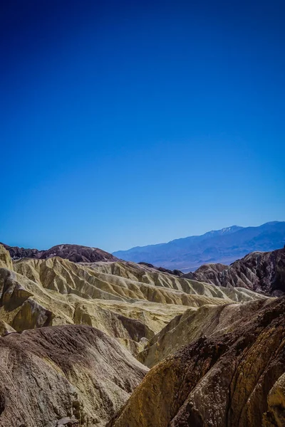 Dağlar sarı ve kahverengi kayalarla kaplıdır. Gökyüzü mavi ve berrak. Dağlar çok yüksek ve gökyüzü çok berrak.