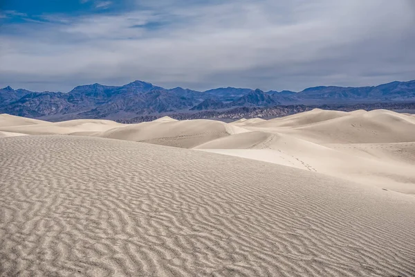 Arka planda mavi gökyüzü olan bir çöl manzarası. Gökyüzü açık ve güneş parlıyor.