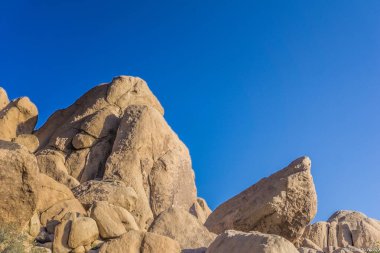 Arka planda mavi gökyüzü olan kayalık bir dağ. Gökyüzü berrak ve parlak ve dağ kayalarla kaplı. Huzurlu ve huzurlu bir manzara. Dağ bir güç hissi veriyor.