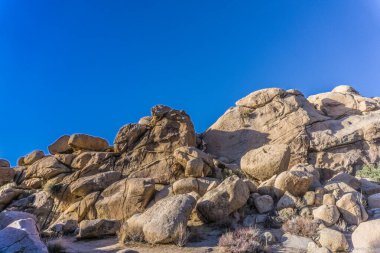 Açık mavi gökyüzü olan kayalık bir yamaç. Kayalar büyük ve pürüzlü, gökyüzü parlak ve berrak. Dayanıklılık ve güç kavramının yanı sıra açıklık ve özgürlük duygusu.