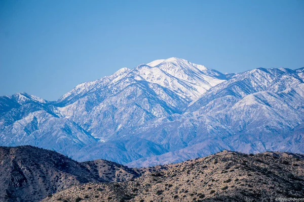 Dağlar karla kaplı ve gökyüzü mavi. Huzurlu ve huzurlu bir sahne.