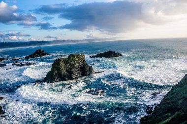 Okyanus sakin ve gökyüzü bulutlu. Dalgalar küçük ve su mavi.