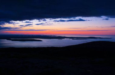 Bir su kütlesinin üzerinde güzel bir günbatımı. Gökyüzü bulutlarla dolu ve güneş batıyor.