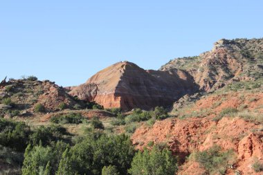 Arkasında dağ olan kayalık bir yamaç. Gökyüzü açık ve mavi. Sükunet ve huzur kavramı