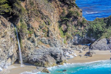Bir şelale okyanusa akıyor. Su berrak ve kayalar pürüzsüz. Huzurlu ve huzurlu bir sahne.