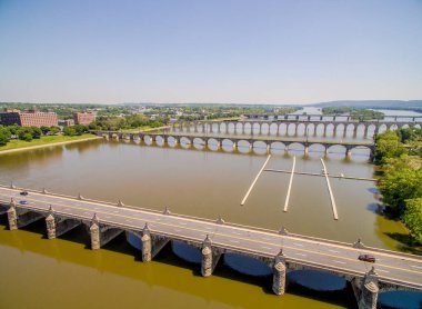Bir köprü aşağıdaki bir şehir manzaralı bir nehri kapsar. Köprü suyla çevrili ve üzerinde birkaç araba var.