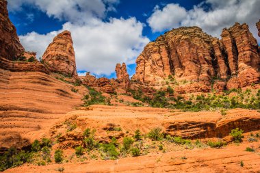 Açık mavi gökyüzü olan kayalık bir dağ sırası. Dağlar da yemyeşil bir bitkiye bürünmüştür. Gökyüzü çoğunlukla açık ve birkaç bulut etrafa saçılmış.