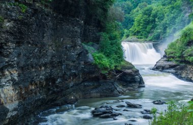 Bir şelale kayalık bir uçurumdan aşağı akıyor. Su berrak ve sakindir, ve çevresi yeşil ağaçlarla doludur. Sahne sakin ve huzurlu, suyun sesiyle.
