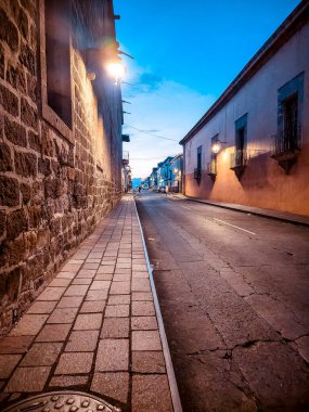 Tuğla kaldırımlı tuğla bir duvar. Kaldırım boş. Sokak karanlık ve sessiz.
