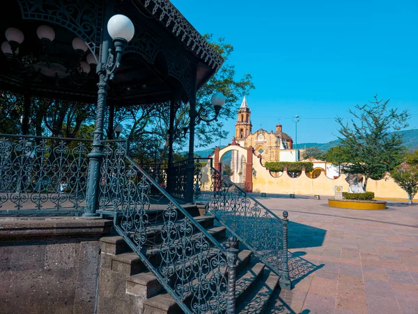 Merdiveni olan küçük bir taraça. Çardak arka planda bir kilise olan bir avluyla çevrili.