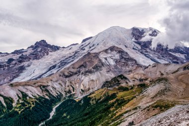 Görkemli dağ zirveleri bulut kaplı yamaçların üzerinde yükselir. Karla kaplı çıkıntılar aşağıdaki engebeli, topraksı vadilerle tezat oluşturuyor. Yoğun yeşil ormanlar daha alçak yamaçlara tutunur. Bulutlu gökyüzü karamsar