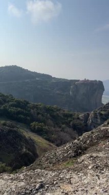 Yunanistan 'daki Meteoras antik kaya sütunları ve Doğu Ortodoks manastırlarının dikey panoramik görüntüsü. Uçsuz bucaksız vadiyi, dik uçurumları ve berrak bir yay altında dağ zirvelerini gösteren yüksek açılı bir çekim..