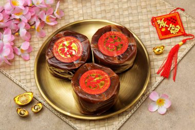 Çin Yeni Yıl süslemeleri ile çevrili altın tabakta üç Nian Gao keki..