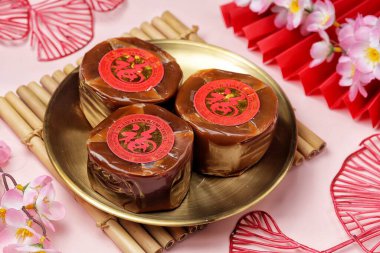 'Fu' silindirli Nian Gao kekleri bambu hasırının üzerinde çiçekli altın tabakta oturuyorlar..