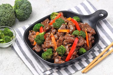 Biftek ve brokoli kızartması bir tabakta servis edilir, taze dilimlenmiş sığır eti ve baharatlı sosla kaplanmış taze yeşil brokoli içerir.