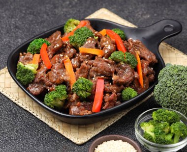 Biftek ve brokoli kızartması bir tabakta servis edilir, taze dilimlenmiş sığır eti ve baharatlı sosla kaplanmış taze yeşil brokoli içerir.