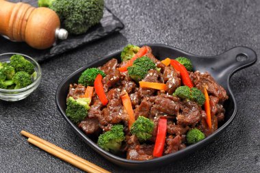 Biftek ve brokoli kızartması bir tabakta servis edilir, taze dilimlenmiş sığır eti ve baharatlı sosla kaplanmış taze yeşil brokoli içerir.