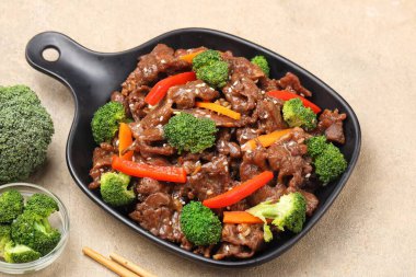 Biftek ve brokoli kızartması bir tabakta servis edilir, taze dilimlenmiş sığır eti ve baharatlı sosla kaplanmış taze yeşil brokoli içerir.