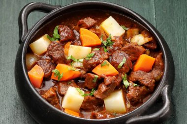 Bir kasede servis edilen sığır eti yahnisinde bol tuzlu sosta haşlanmış et, patates ve sebze parçaları yer alıyor. Macar kebabı.