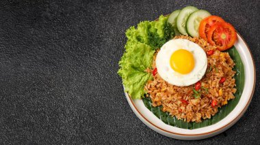 Nasi goreng. Dilimlenmiş salatalık ve domatesli kızarmış yumurta.