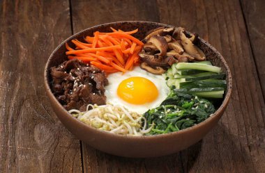 Bibimbap, yanında sebze, biftek, yumurta ve baharatlı gochujang sosu bulunan bir kase beyaz pirinç şeklinde bir Kore yemeğidir..