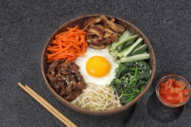 Bibimbap, yanında sebze, biftek, yumurta ve baharatlı gochujang sosu bulunan bir kase beyaz pirinç şeklinde bir Kore yemeğidir..