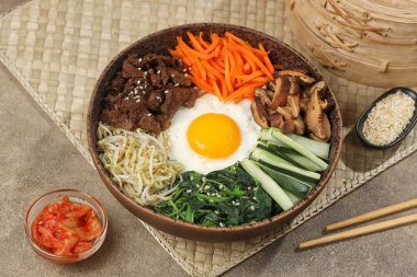 Bibimbap, yanında sebze, biftek, yumurta ve baharatlı gochujang sosu bulunan bir kase beyaz pirinç şeklinde bir Kore yemeğidir..