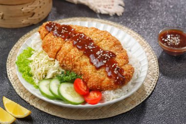 Tonkatsu, kızarmış domuz pirzolası, dilimlenmiş lahana, limon dilimleri ve lezzetli sosla servis edilen popüler bir Japon yemeği..