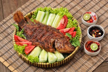 Ikan Bakar, taze salatalık ve domatesle servis edilen Endonezya usulü ızgara tilapia balığı.