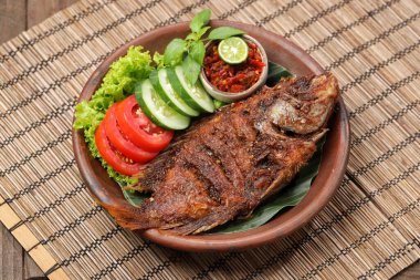 Ikan Bakar, taze salatalık ve domatesle servis edilen Endonezya usulü ızgara tilapia balığı.
