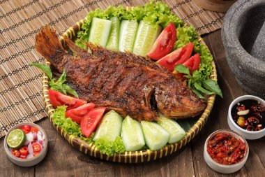 Ikan Bakar, taze salatalık ve domatesle servis edilen Endonezya usulü ızgara tilapia balığı.