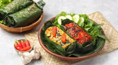 Geleneksel bir Endonezya yemeği olan Nasi Bakar, muz yapraklarına sarılmış tavuklu baharatlı pirinç..
