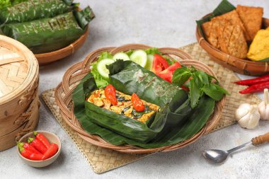 Geleneksel bir Endonezya yemeği olan Nasi Bakar, muz yapraklarına sarılmış tavuklu baharatlı pirinç..