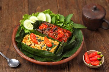 Geleneksel bir Endonezya yemeği olan Nasi Bakar, muz yapraklarına sarılmış tavuklu baharatlı pirinç..