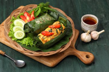 Geleneksel bir Endonezya yemeği olan Nasi Bakar, muz yapraklarına sarılmış tavuklu baharatlı pirinç..