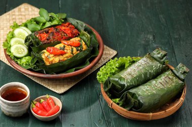 Geleneksel bir Endonezya yemeği olan Nasi Bakar, muz yapraklarına sarılmış tavuklu baharatlı pirinç..