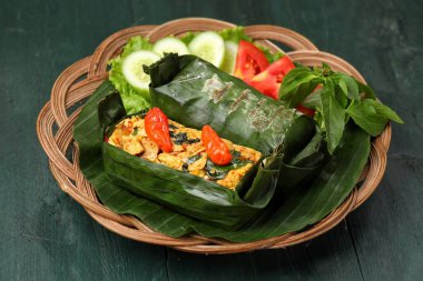 Geleneksel bir Endonezya yemeği olan Nasi Bakar, muz yapraklarına sarılmış tavuklu baharatlı pirinç..