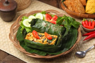 Geleneksel bir Endonezya yemeği olan Nasi Bakar, muz yapraklarına sarılmış tavuklu baharatlı pirinç..