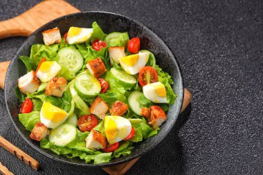 Tavuklu sağlıklı salata, yumurta, marul, domates, yumurta, soğan, kızarmış ekmek, marul, siyah tabak. Sağlıklı kahvaltı. Temizle