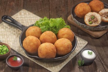 Ahşap masada tavada soslu kızarmış köfte.