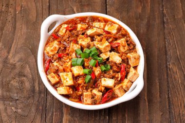 Acı biber soslu Asya baharatlı tofu ve ahşap bir masada domates..