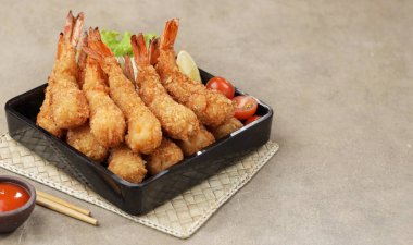 Ahşap zemin üzerinde soslu kızarmış karides ve kalamar tempurası.