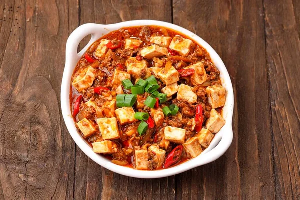 Acı biber soslu Asya baharatlı tofu ve ahşap bir masada domates..