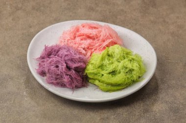 Üç kepçe renkli dondurma beyaz tabakta desenli yüzeye yerleştirilmiş.