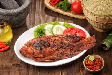 Kızarmış balık taze sebze ve acılı sosla beyaz tabağa konur.