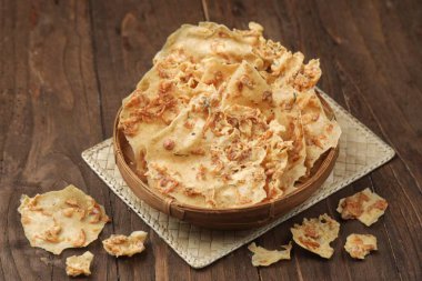 Tahta masaya yerleştirilmiş gevrek, kızarmış patates cipsiyle dolu bir kase..