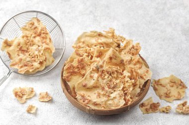 Hafif desenli arka planda gevrek atıştırmalıklarla dolu ahşap bir kase.