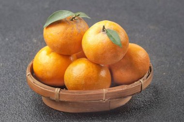 Birkaç parlak turuncu mandalinayla dolu sepet desenli yüzeyde duruyor.